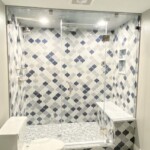 large glass enclosure shower with blue and gray tile
